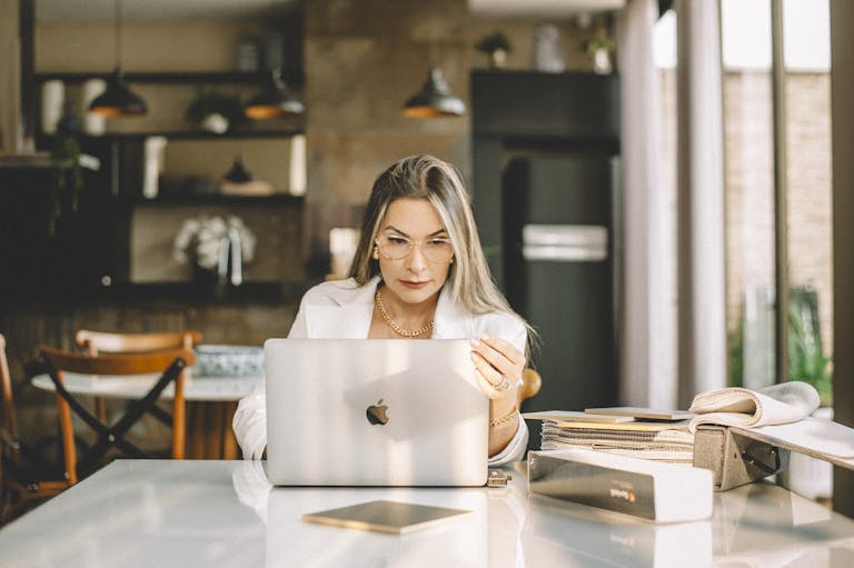 A woman in a stylish kitchen is focused on her laptop, embodying a modern work-from-home lifestyle.