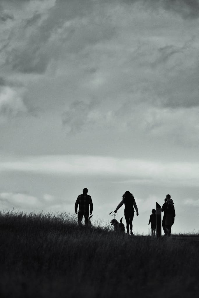 Artistic silhouette of people walking on a hill under dramatic skies, evoking a serene and contemplative mood.